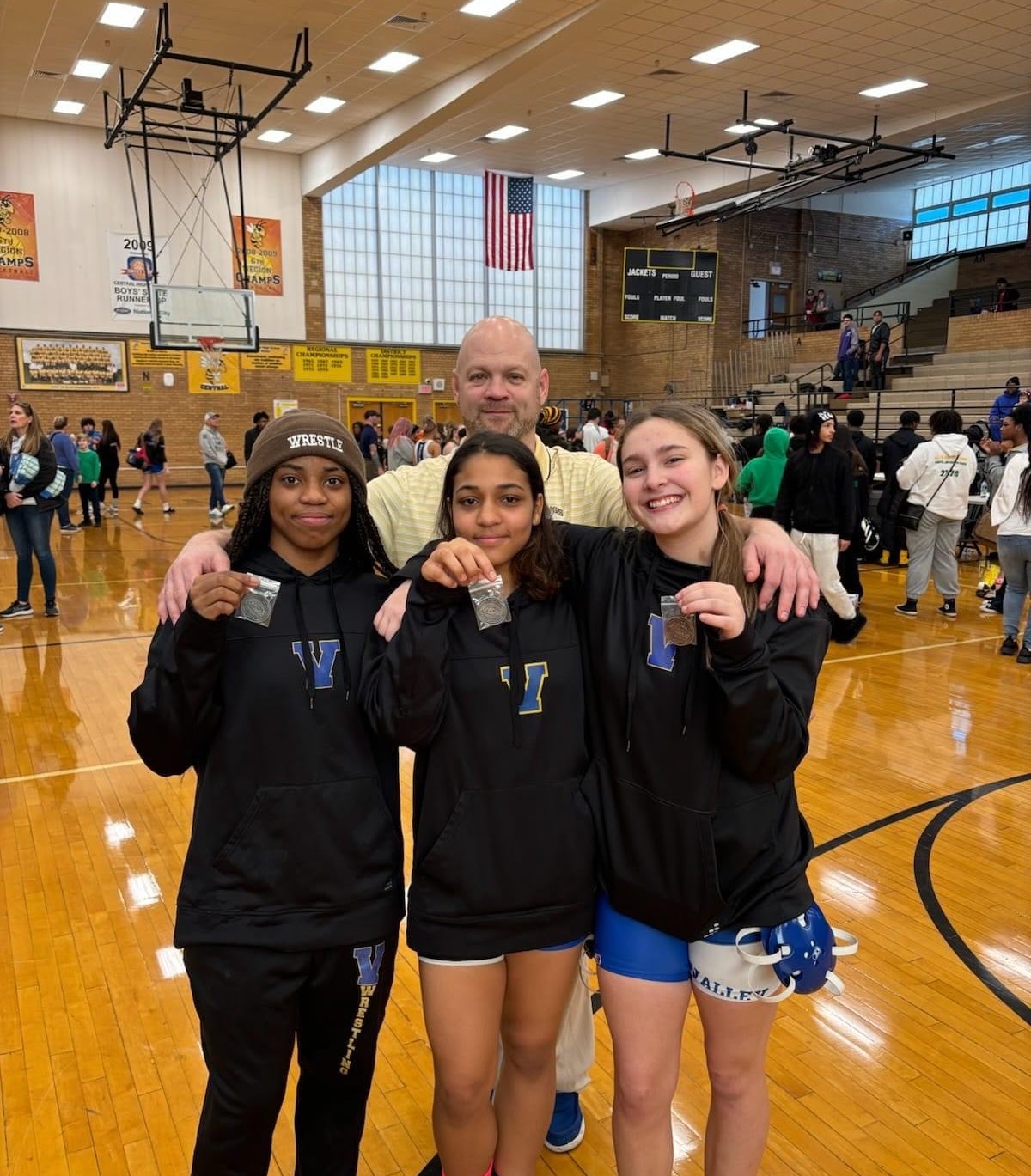 coach and girls wrestling showing their medals