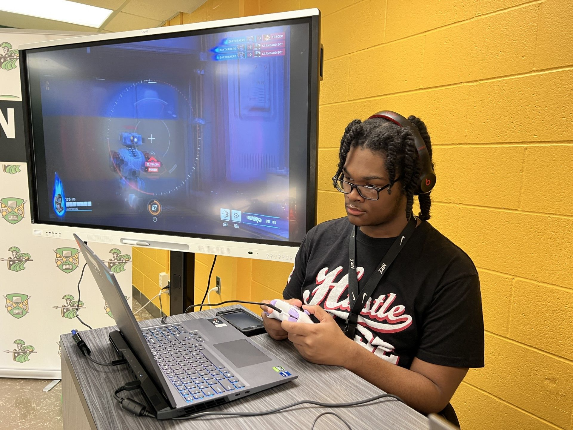 student playing a game on a large screen while looking at laptop