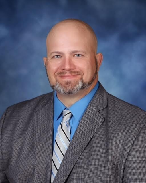 A professional bald man wearing a suit and tie, exuding confidence and authority.