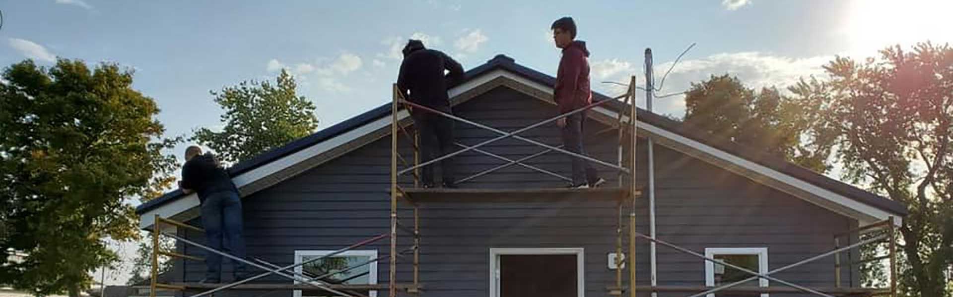 students working on the side of a house on scafolding