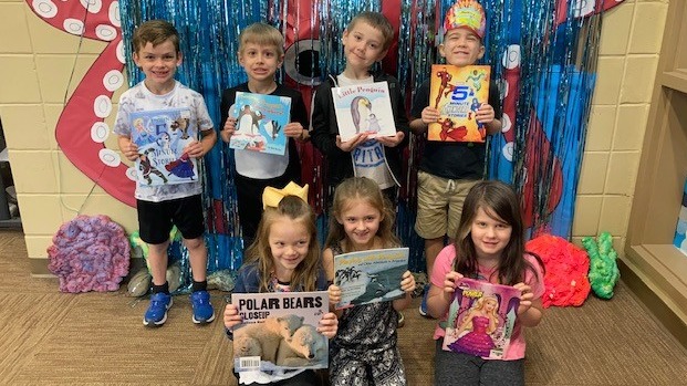 kids showing their drawings to the camera