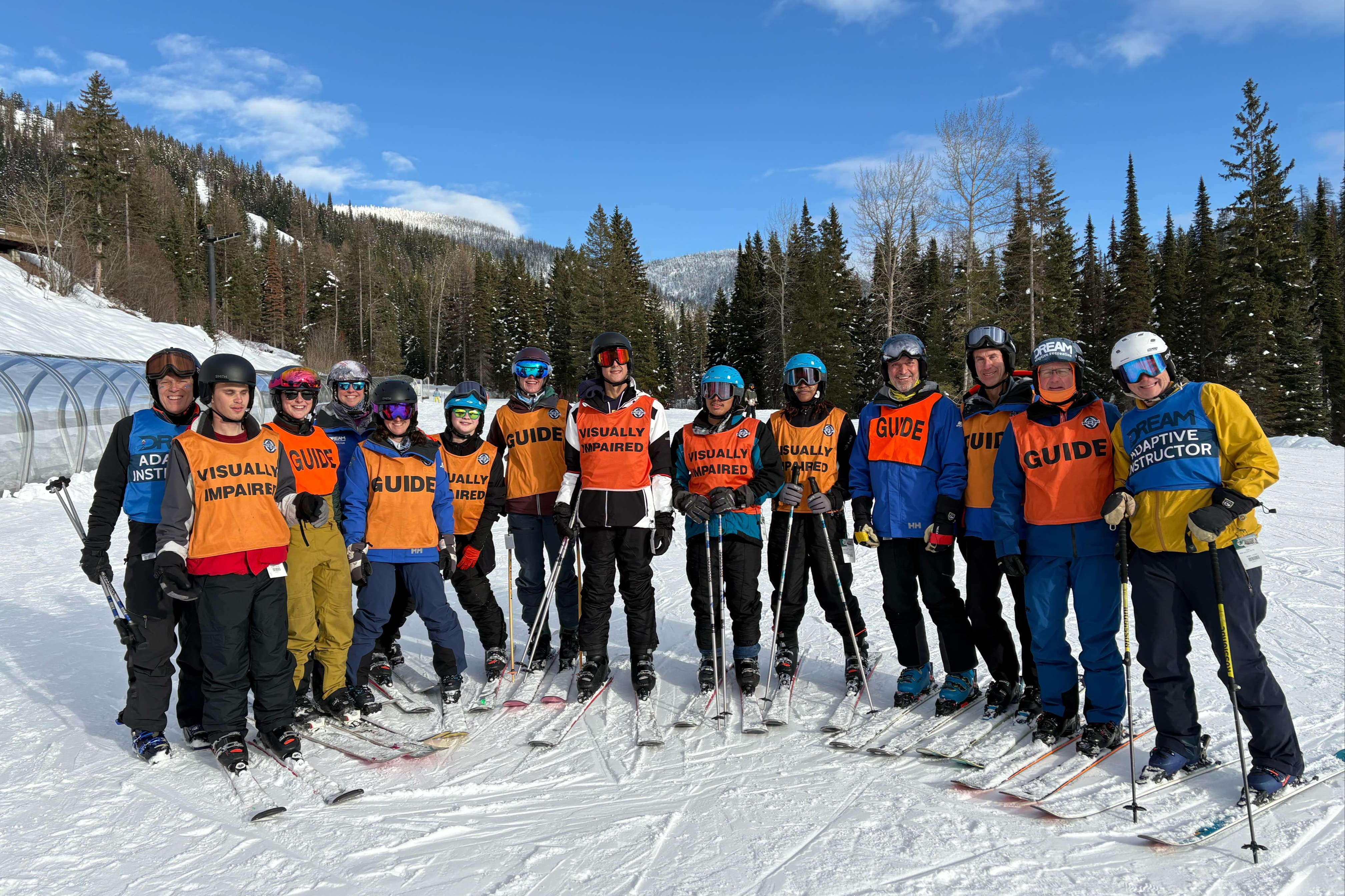 Blind Ski Club members on top of a snowy mountain with skis and poles.