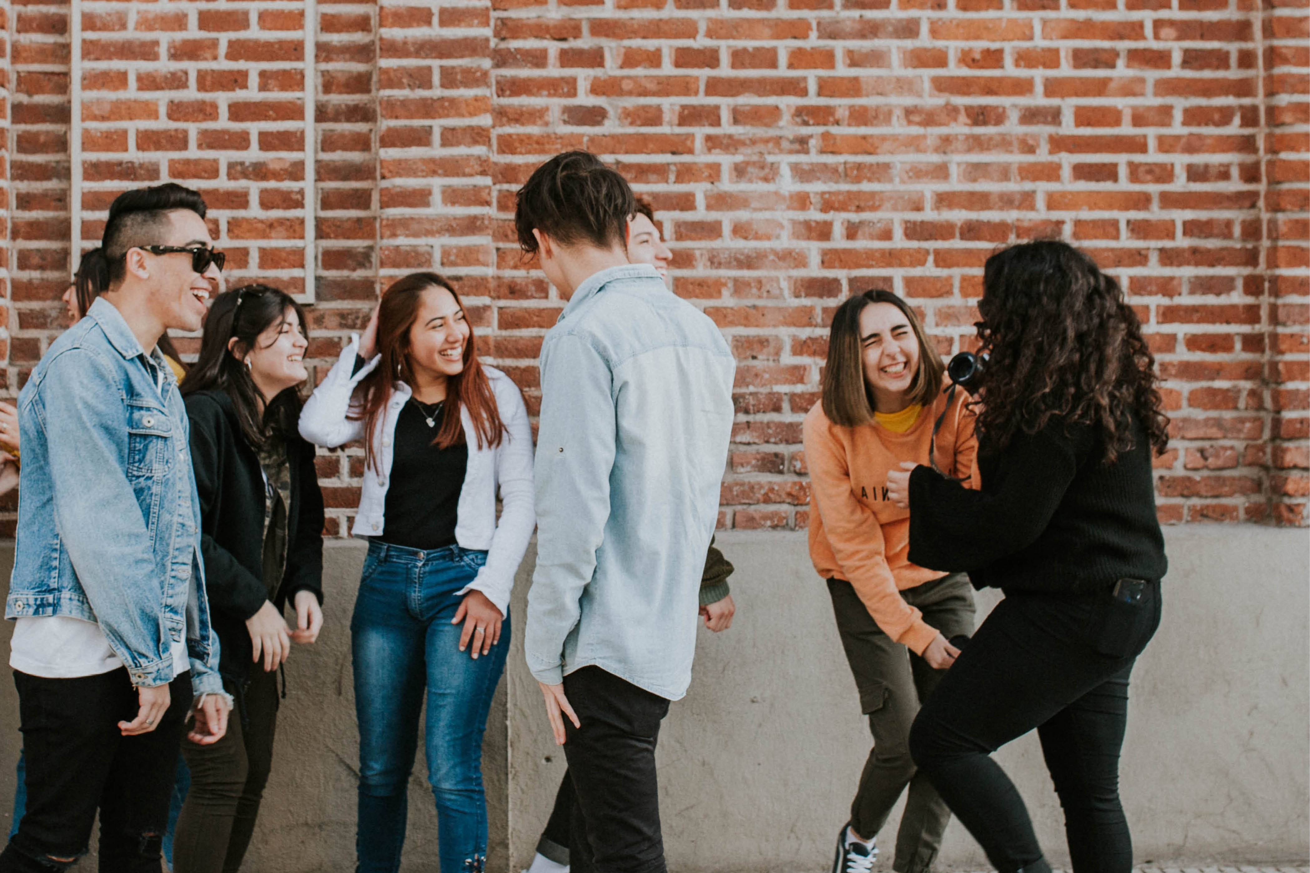Group of teenagers laughing together outside of a brick building
