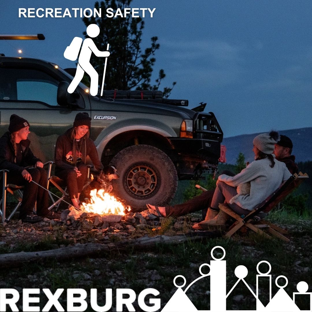 4 young adults in camping chairs on a hill with a campfire in the middle of them and the front half of a truck visible behind them