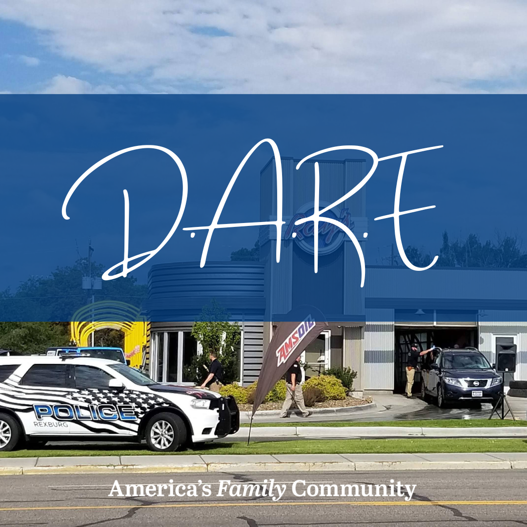 Rexburg Police car in front of car wash with text "D.A.R.E."