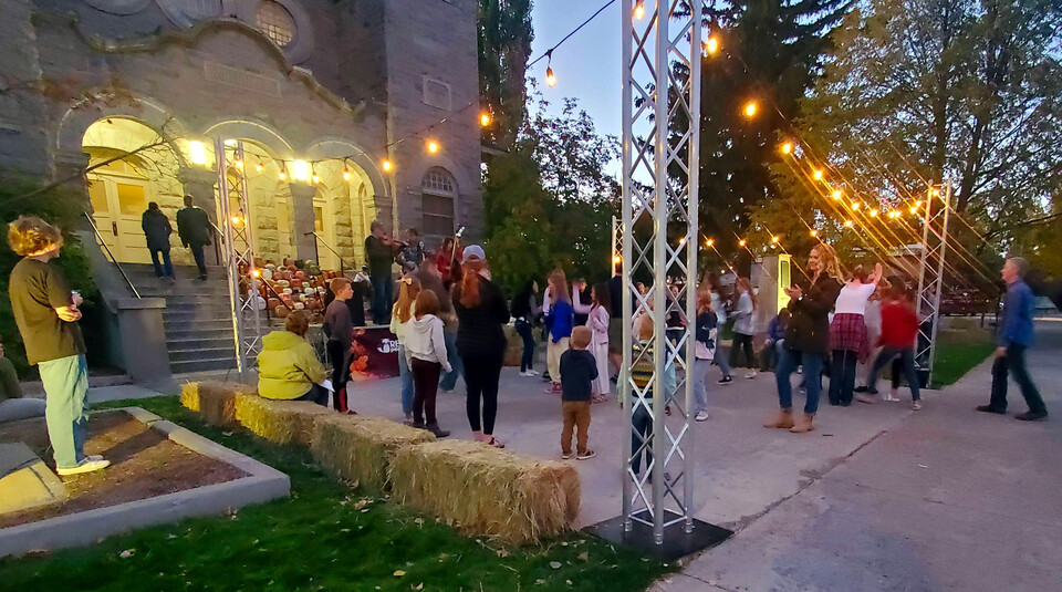 People dancing in front of the Tabernacle with a band playing in front of the front steps and lights hanging overhead.