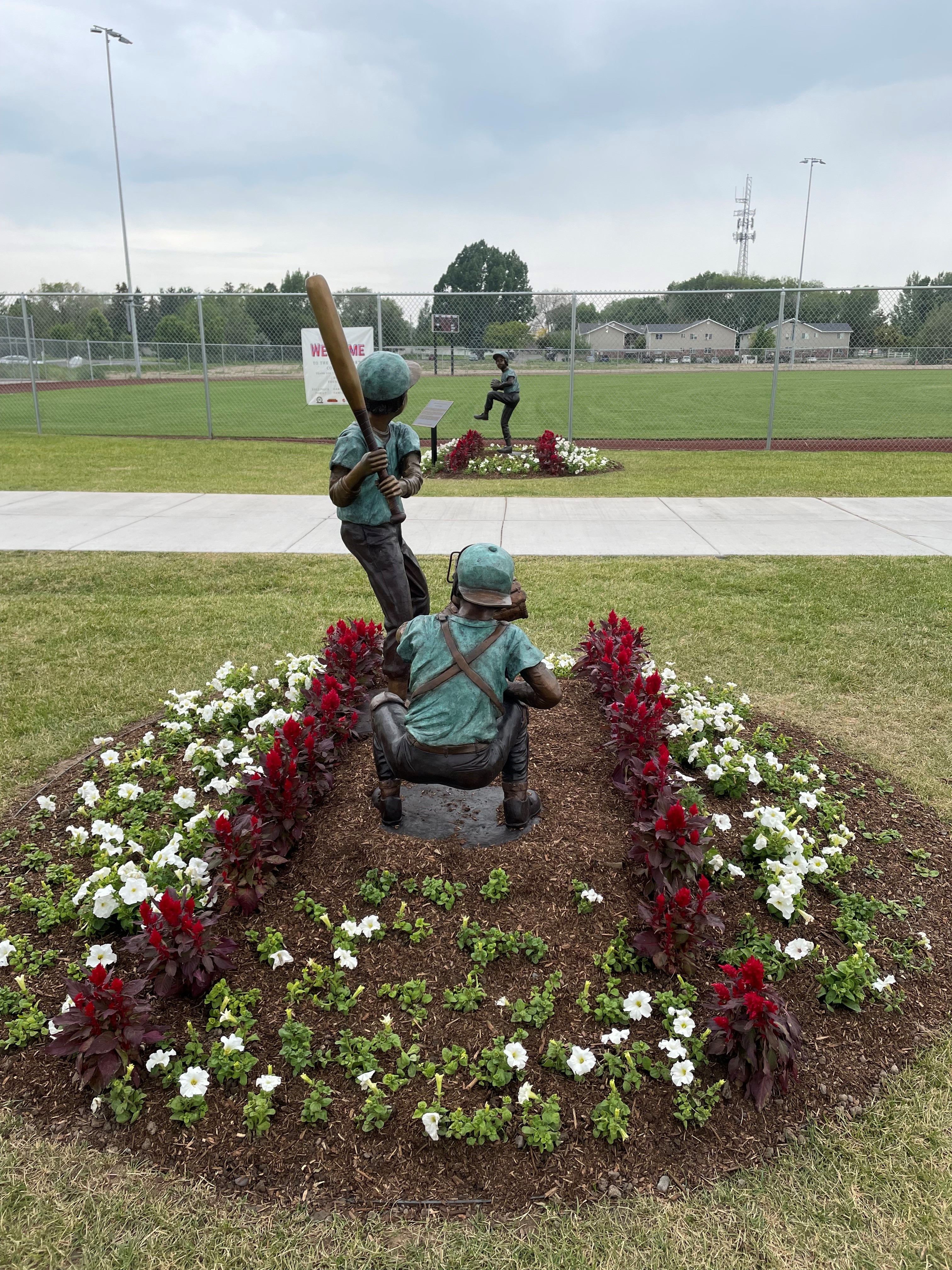 statues of baseball players surrounded by flowers at the DonJo sports fields