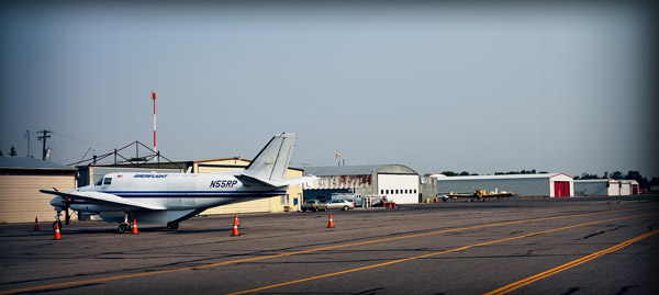 airplane docked outside a hangar bay off the tarmac