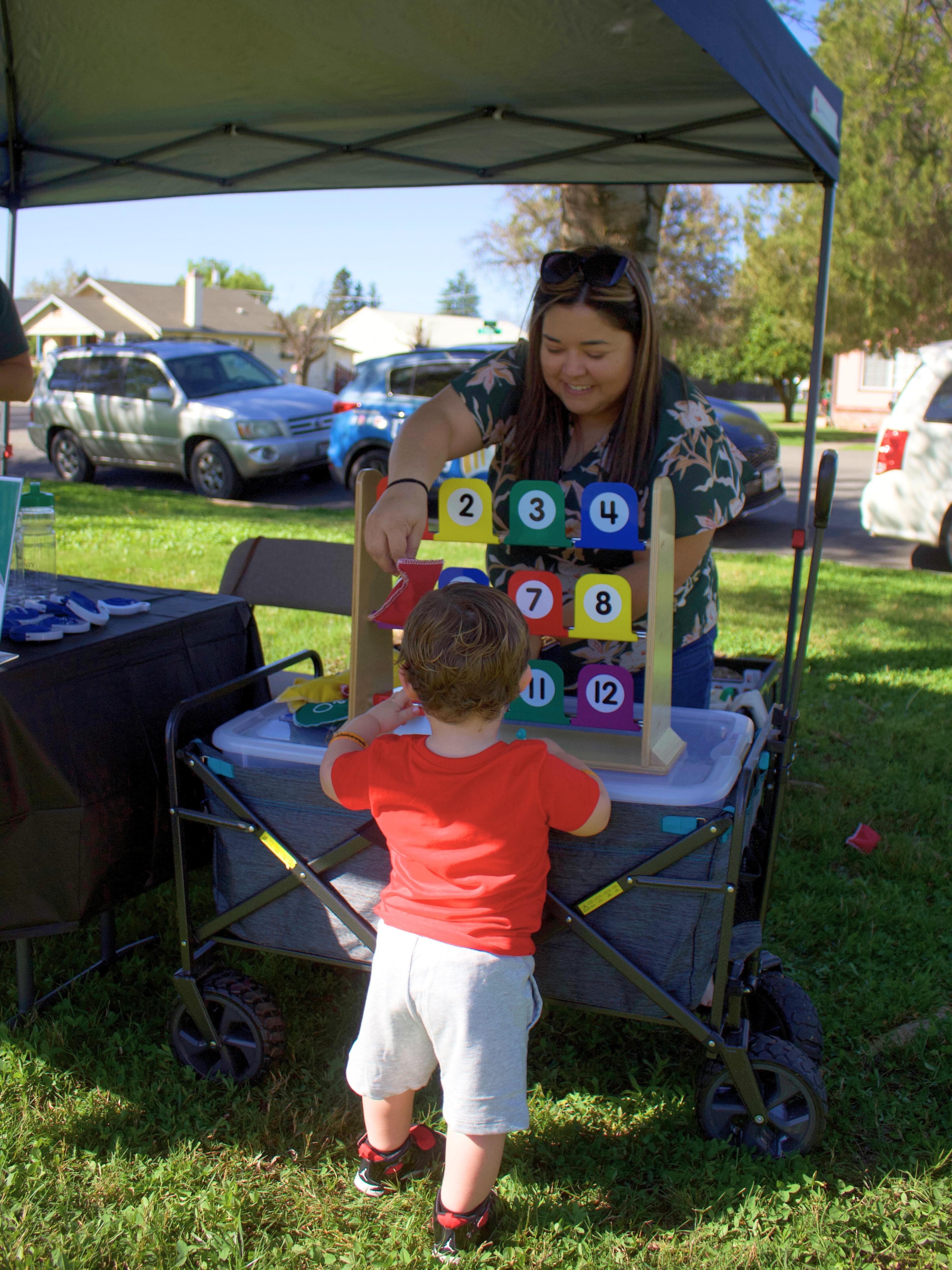 Adult female helping child play a numbered game at table
