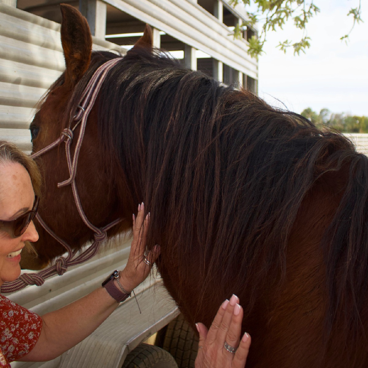Nikole Baker smiling with hands on horse