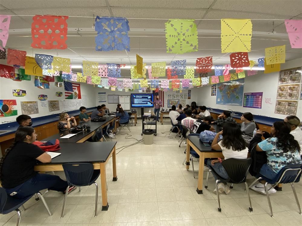 Students in a classroom listening to a teacher