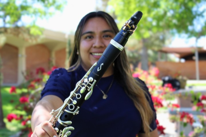 Ms. Bailon holding a clarinet with flowers in the background