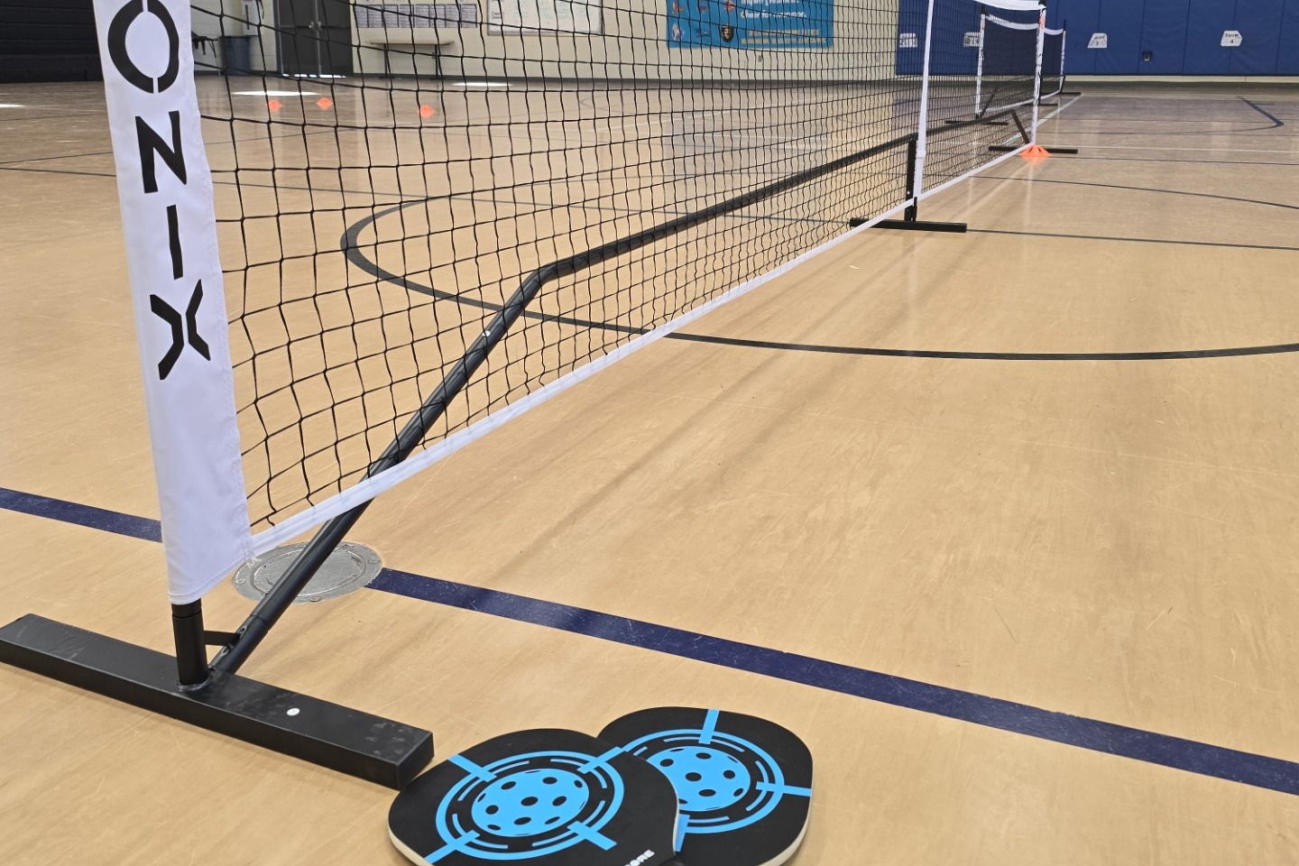 Pickleball rackets and net in an empty gym