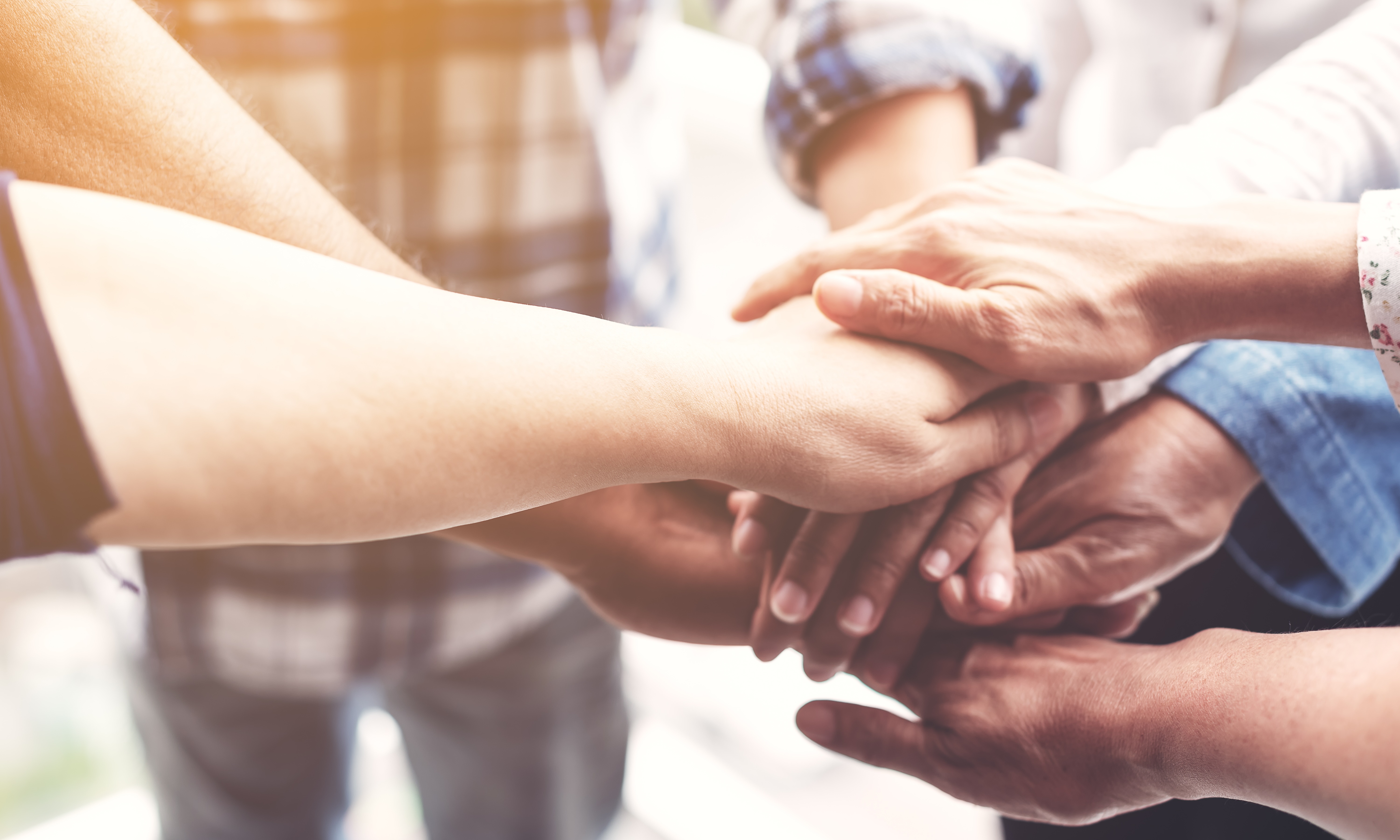 A group of individuals reaching out to each other in a handshake, symbolizing unity and cooperation.