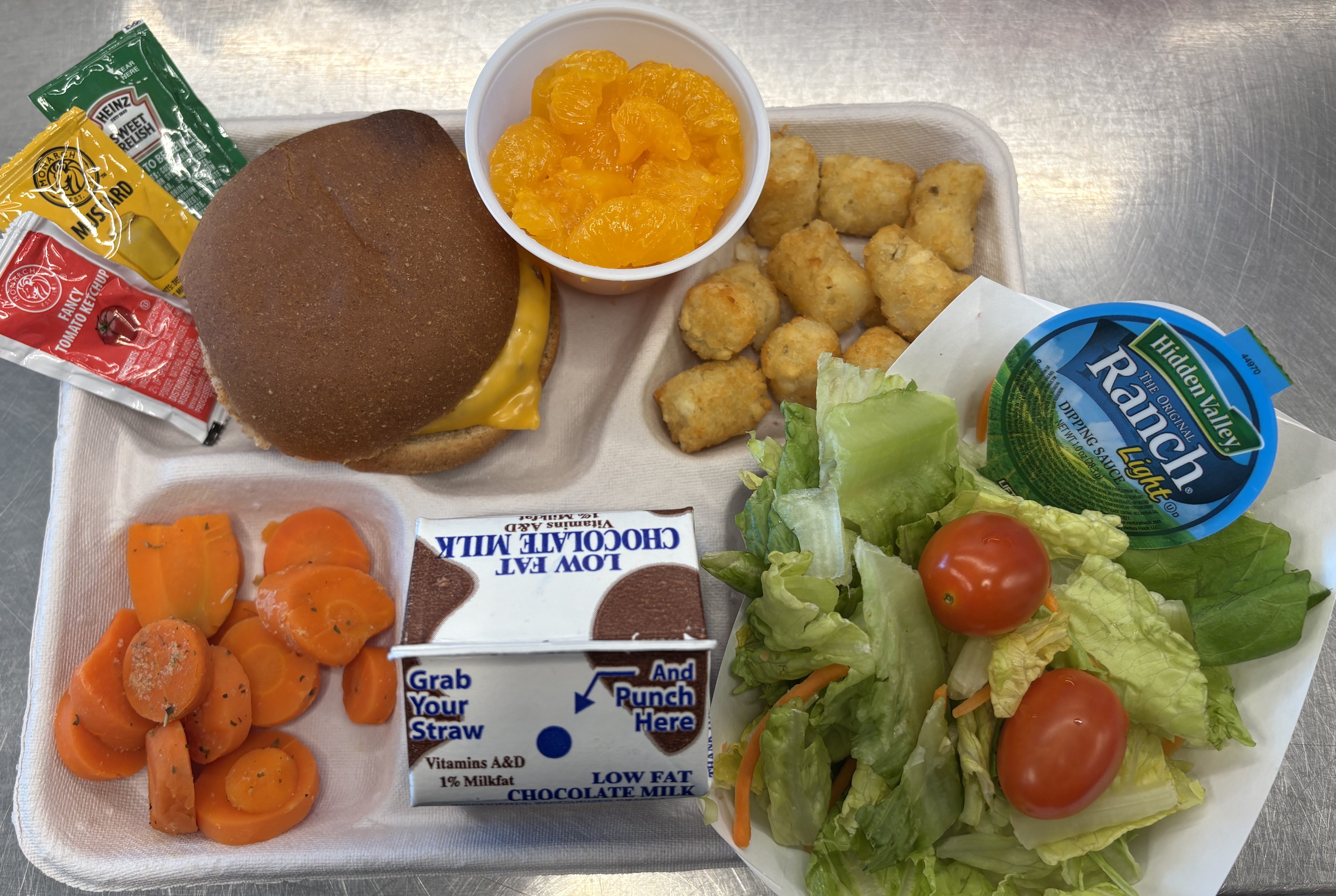 Lunch served on 9.16.2025- Cheeseburger, Tator Tots, Carrots, Cupped Peaches, Salad  & Chocolate Milk
