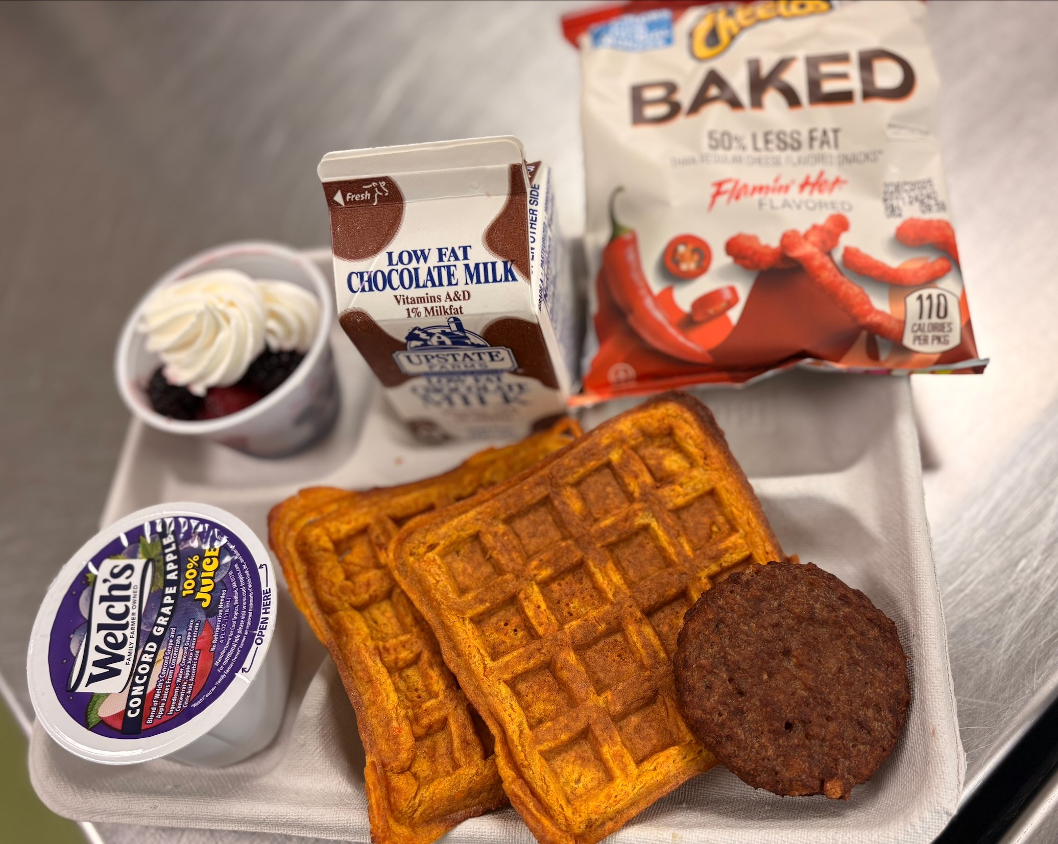 School 198- Lunch served on 10.2.25 NY Carrot Waffles, Plant-based breakfast sausage, Grape Apple juice, Mixed Berry cup-whipped cream, Baked flaming Cheetos & Chocolate Milk