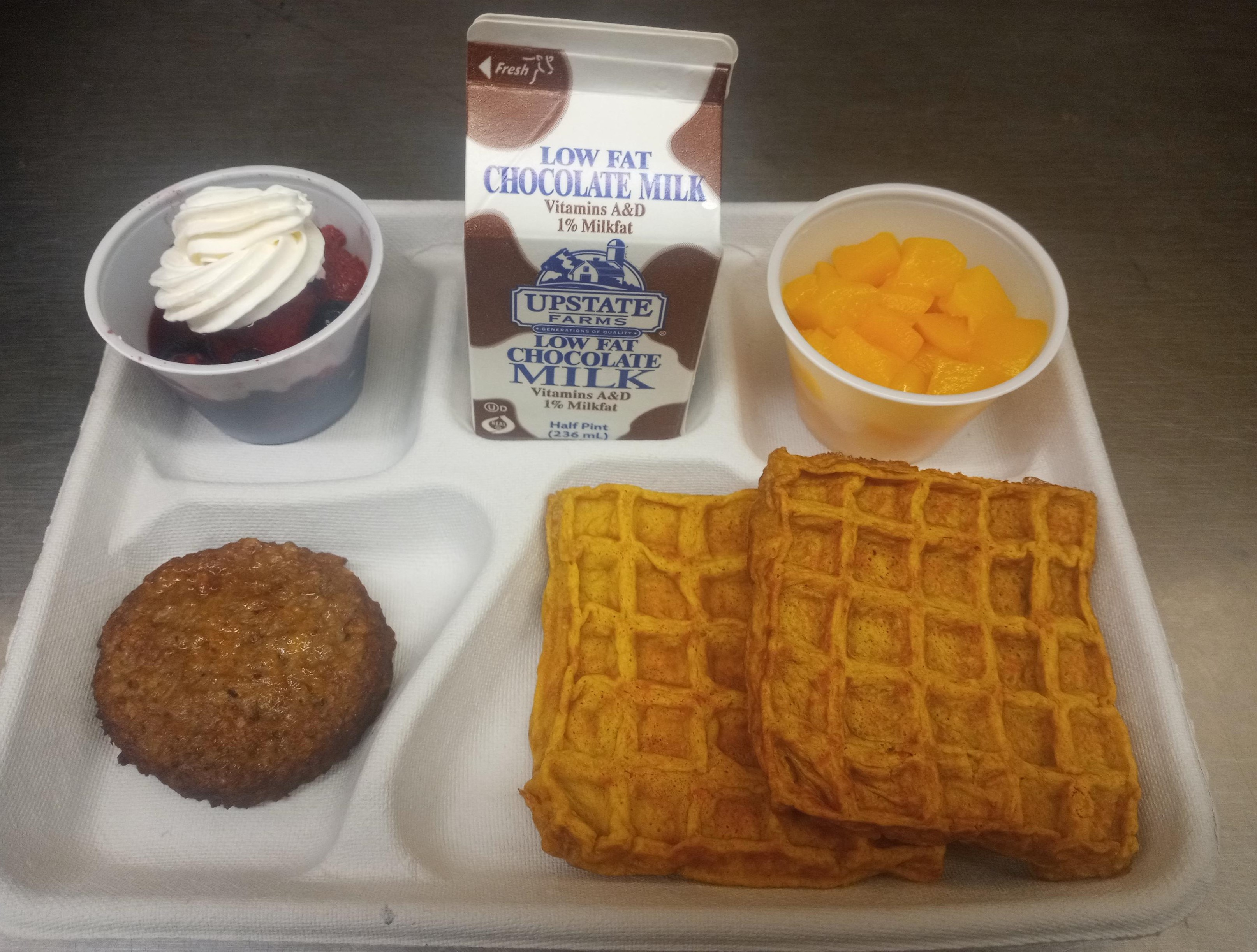 School 207- Lunch served on 10.2.25 NY Carrot Waffles, Plant-based breakfast sausage, Mixed Berry cup-whipped cream, Peaches & Chocolate Milk