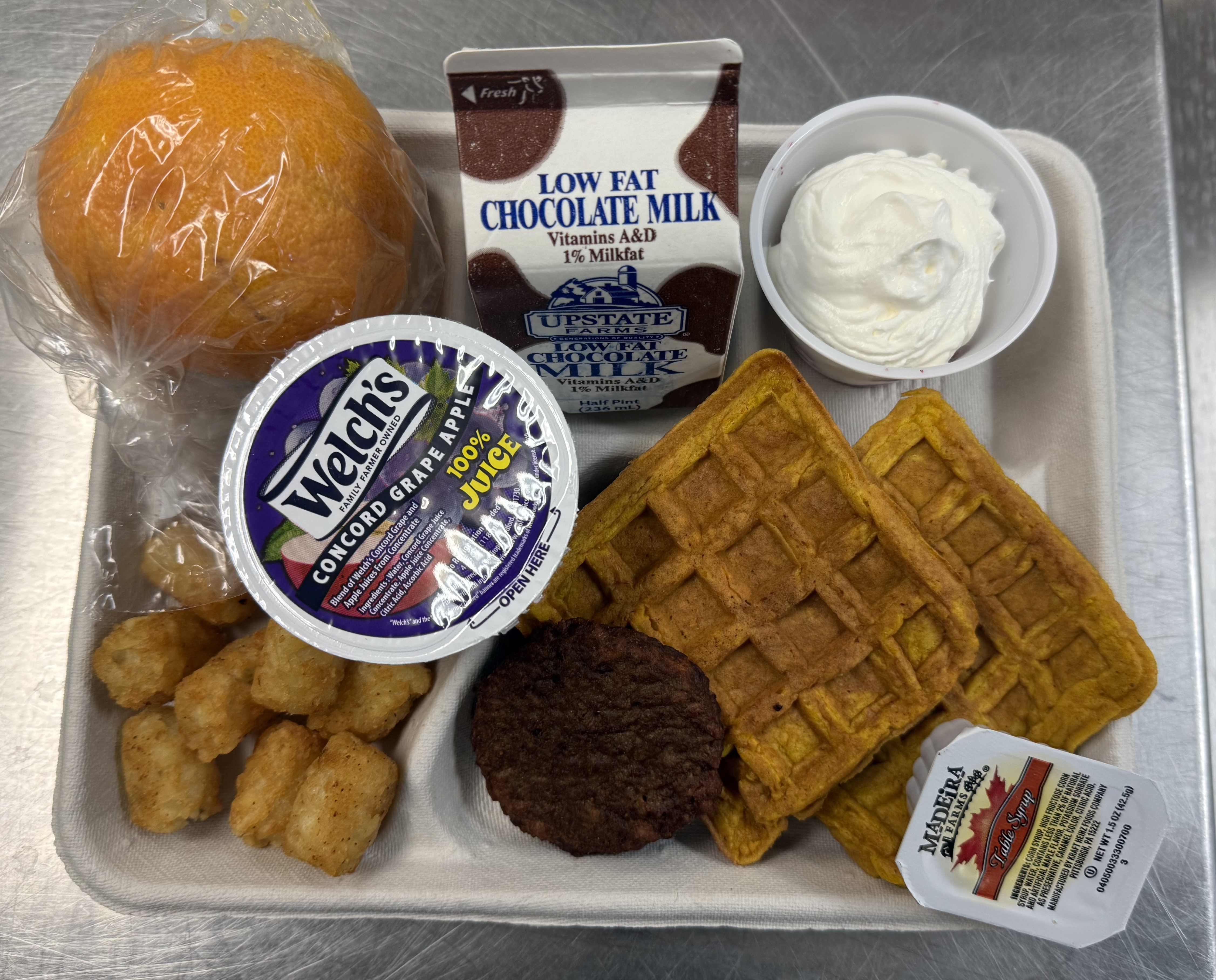 School 48- Lunch served on 10.2.25 NY Carrot Waffles, Plant-based breakfast sausage, Grape Apple juice, Mixed Berry cup-whipped cream, Tator tots, orange & Chocolate Milk