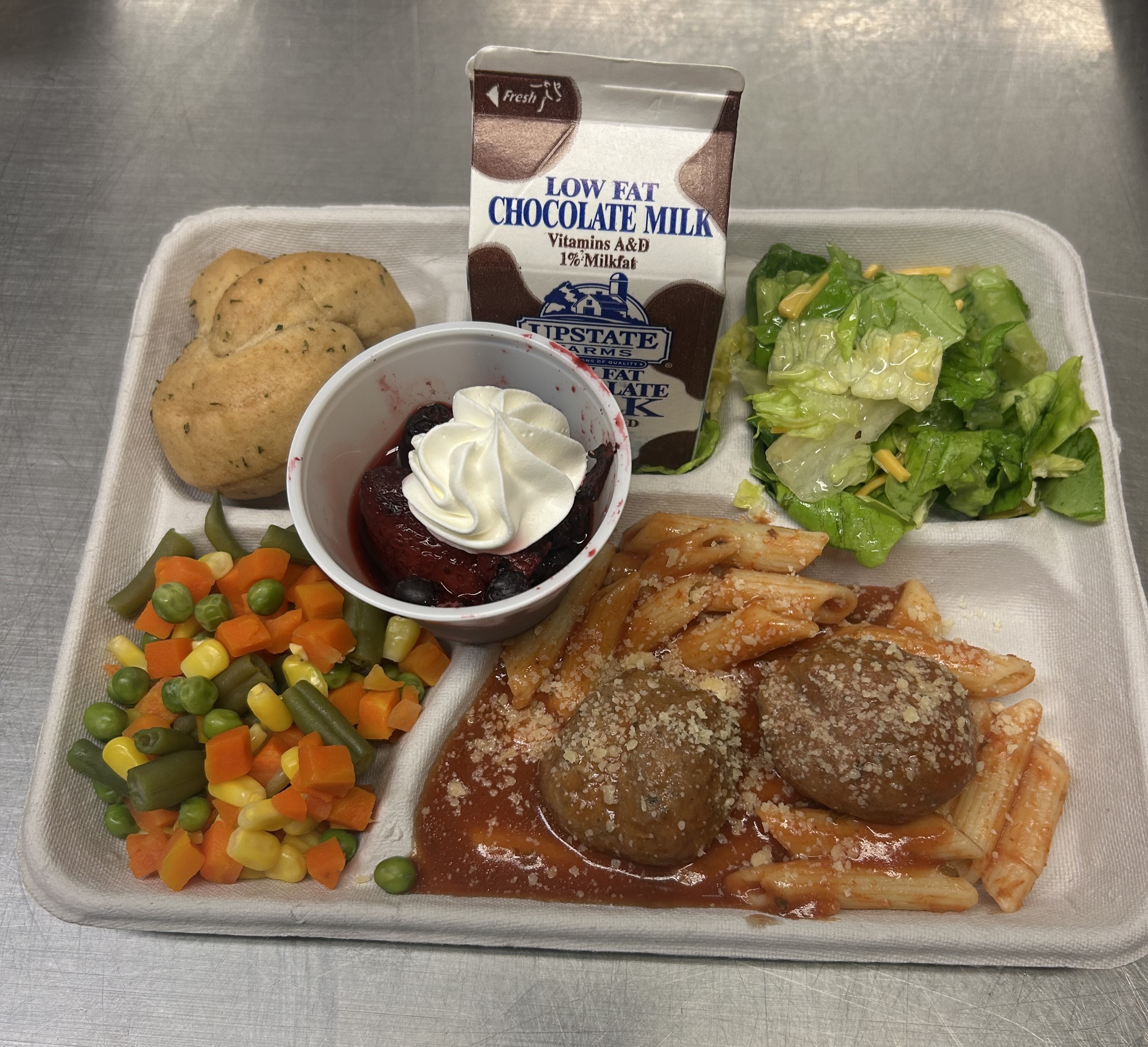 Lunch served 10.3.2025 Penne pasta with Meatballs & Marinara, Garden salad, vegetable medley, Mixed Berries, Garlic Knot & Chocolate Milk