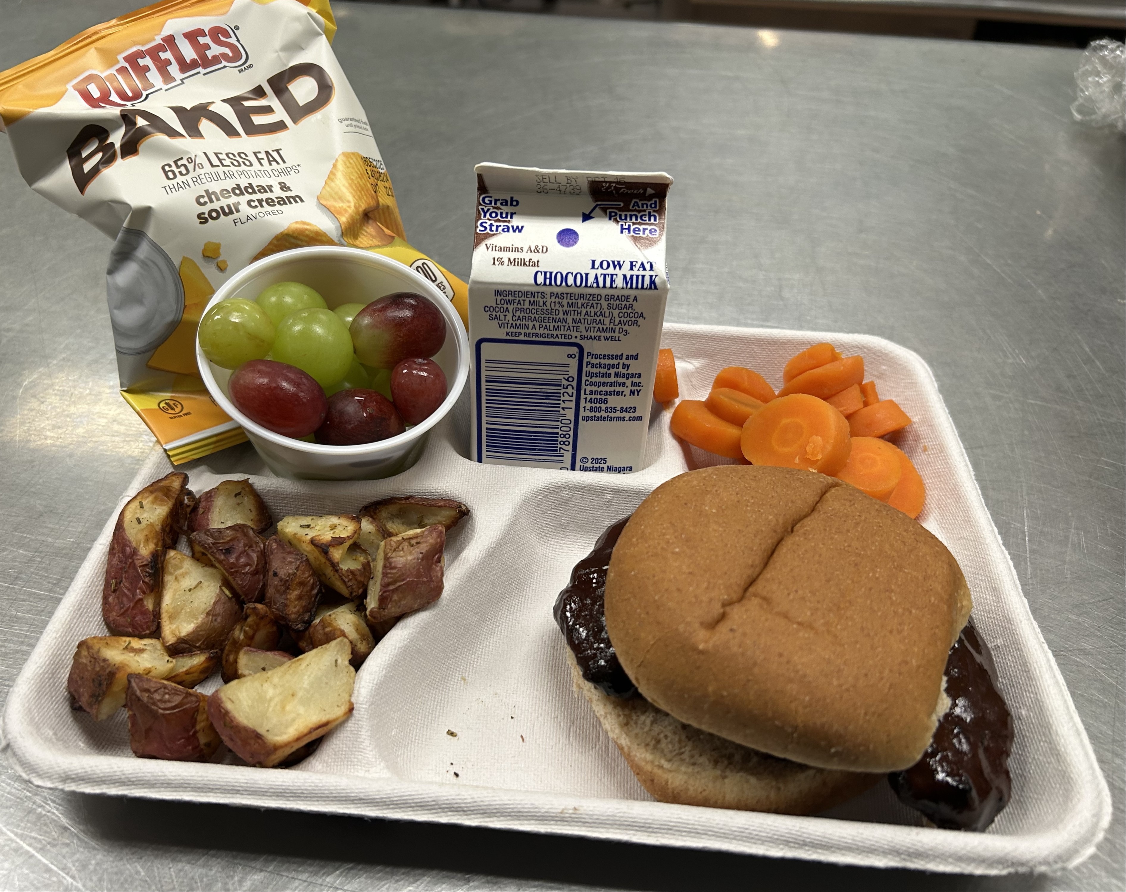 School 305- Lunch served on 10.8.25 BBQ Ribs on WG Burger Bun, Roasted Potatoes, Vegetable Medley, Grapes, Baked Chips & Chocolate milk