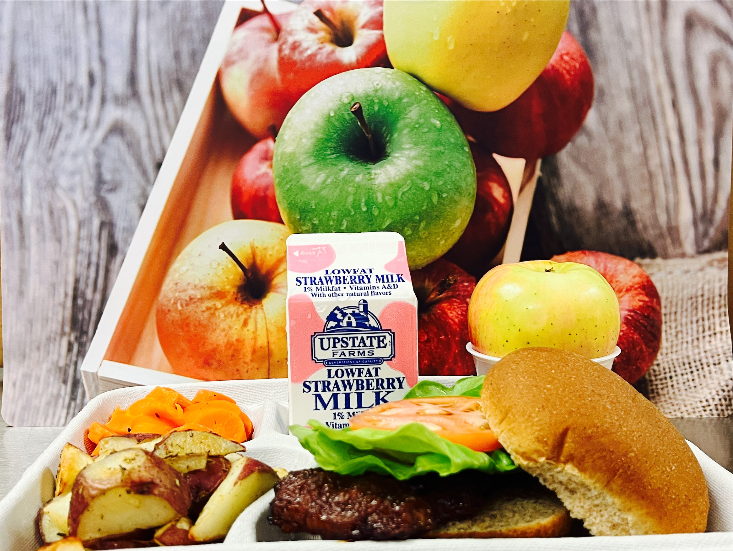 School 205- Lunch served on 10.8.25 Cheeseburger, Roasted Potatoes, Carrot Coins, Apple & Strawberry Milk