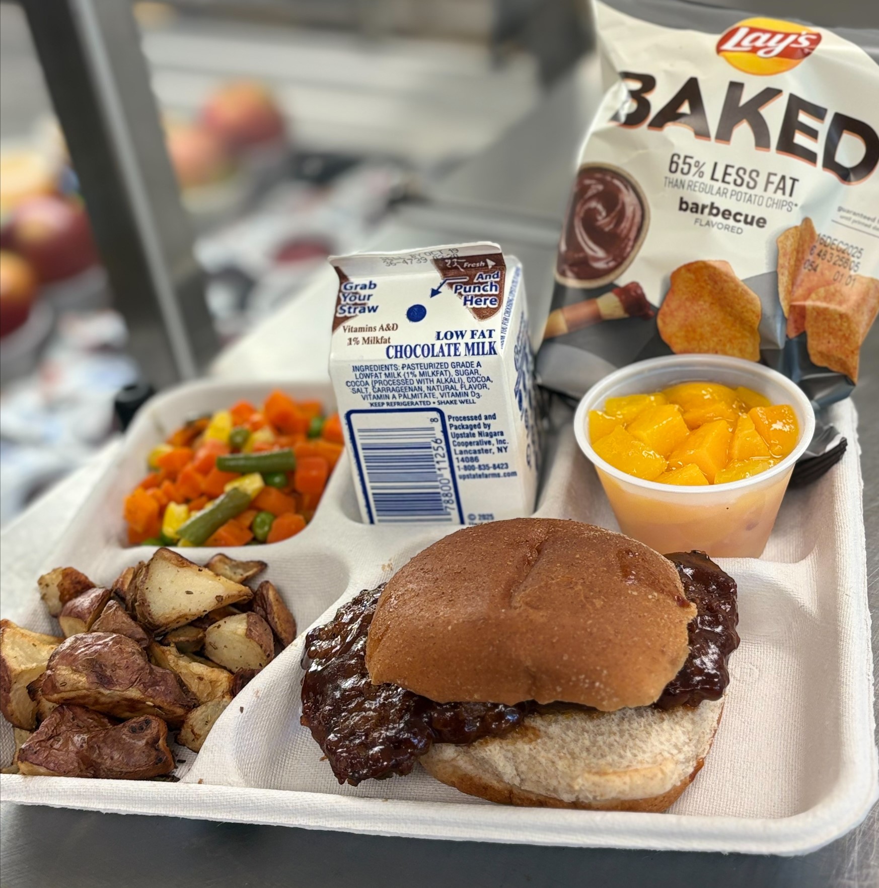 School 198- Lunch served on 10.8.25 BBQ Ribs on WG Burger Bun, Roasted Potatoes, Vegetable Medley, Peaches, Baked BBQ Lays & Chocolate milk