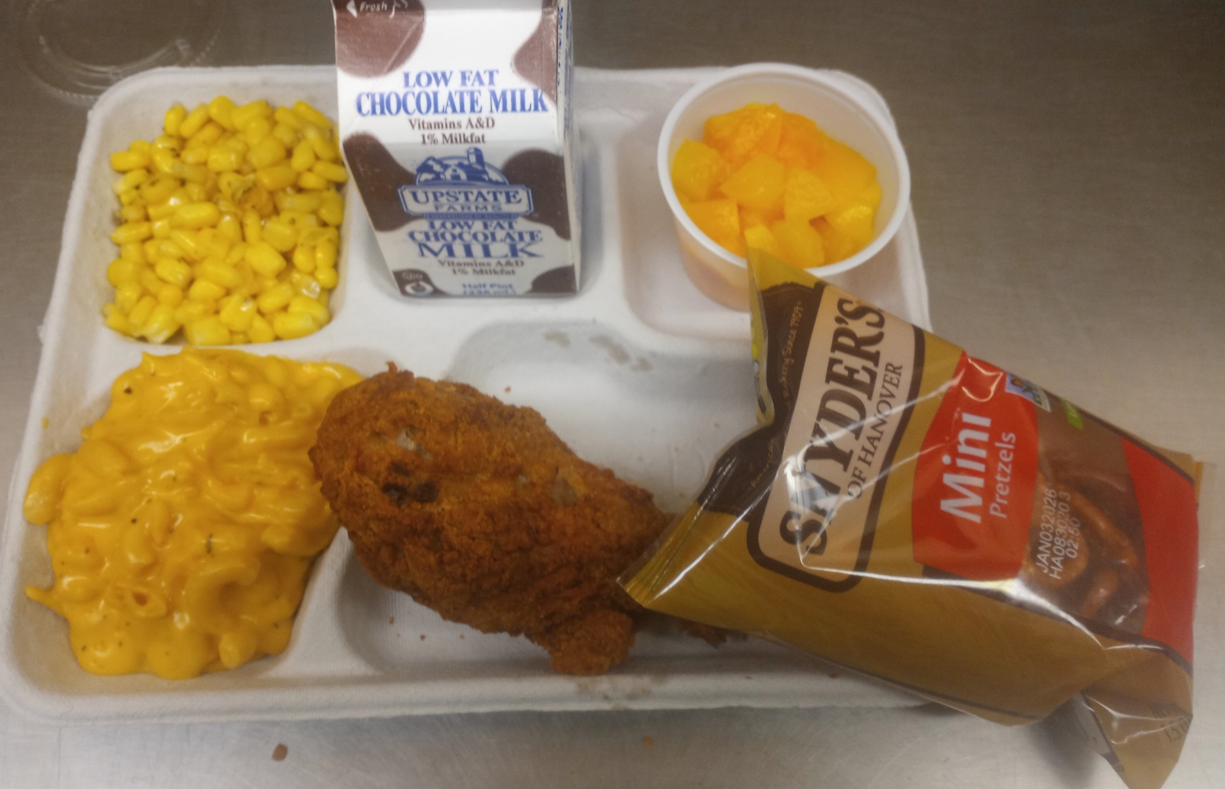 School 207- Lunch served on 10.23.25 Breaded Chicken Drumstick, Macaroni & Cheese, Sweet Corn, Pretzels, Cupped Peaches & Chocolate Milk