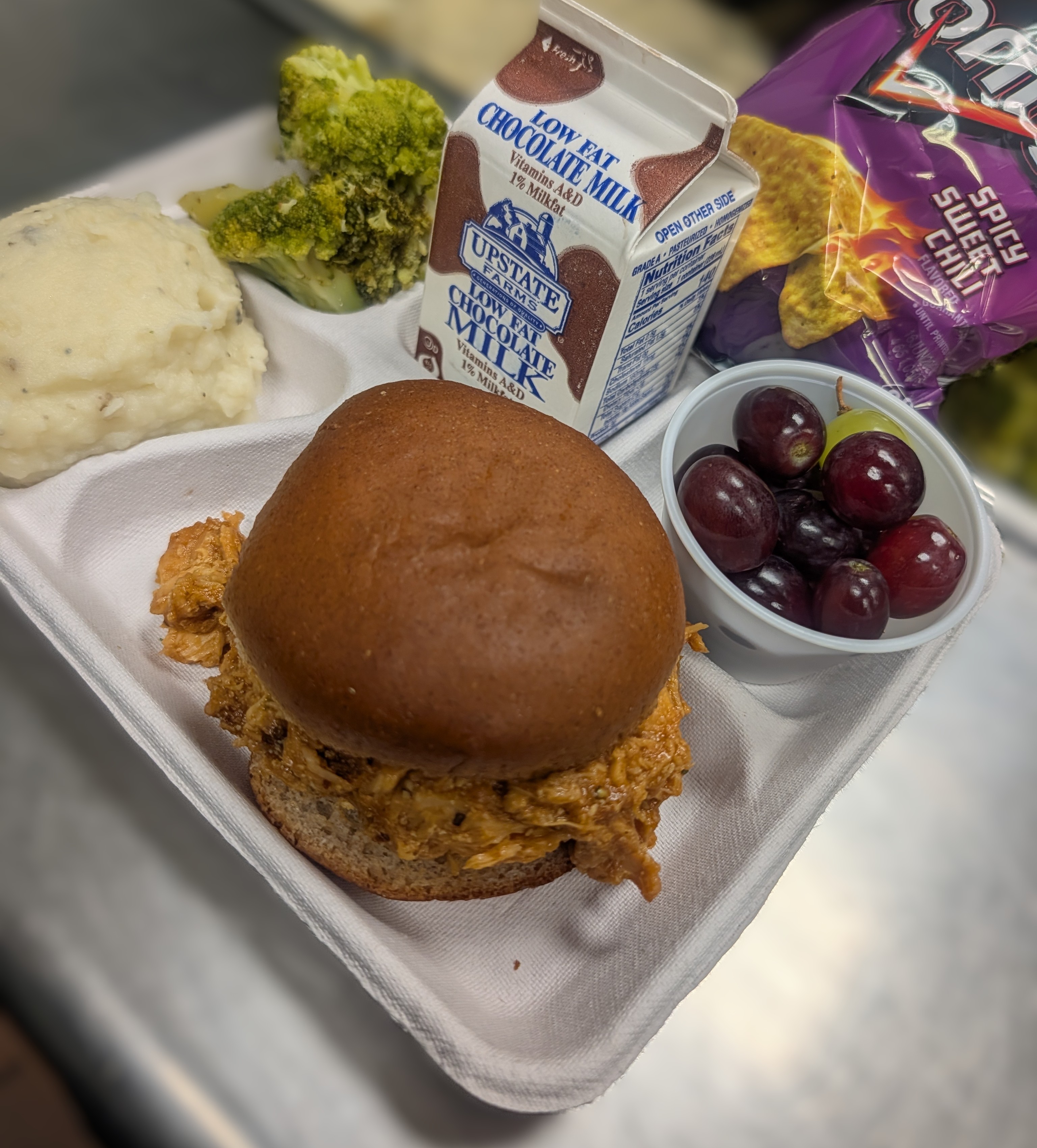 School 305- Lunch served on 3.13.26 ,BBQ pulled chicken on a WG bun, mashed potatoes, roasted broccoli, grapes, doritos and chocolate milk