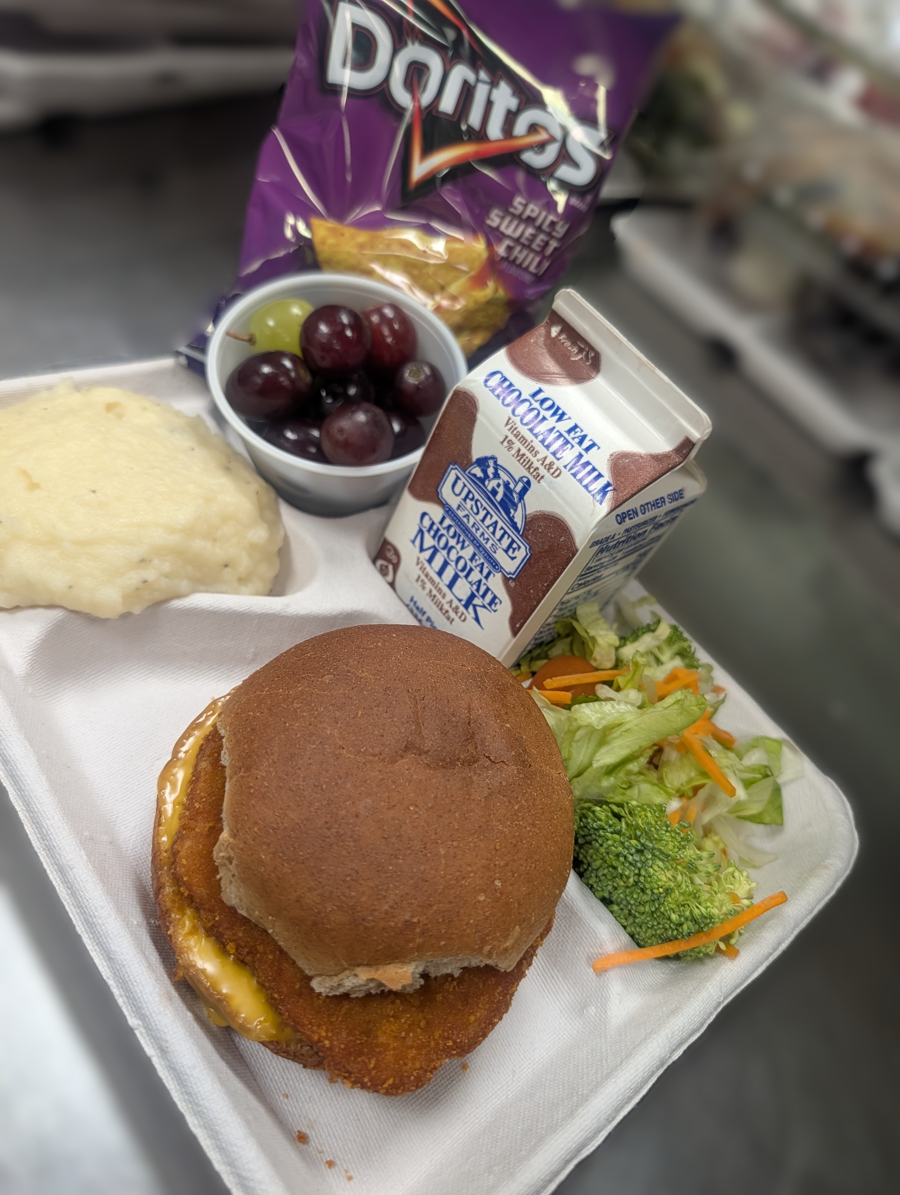School 305- Lunch served on 3.13.26 ,Halal chicken patty on a WG bun, mashed potatoes, garden salad, grapes, doritos and chocolate milk