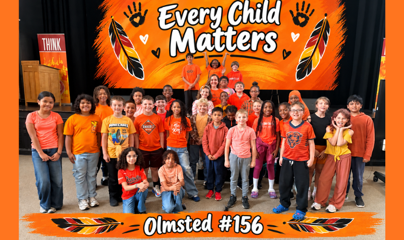 Group of Teachers and students from school 156 in wearing orange shirts in an auditorium