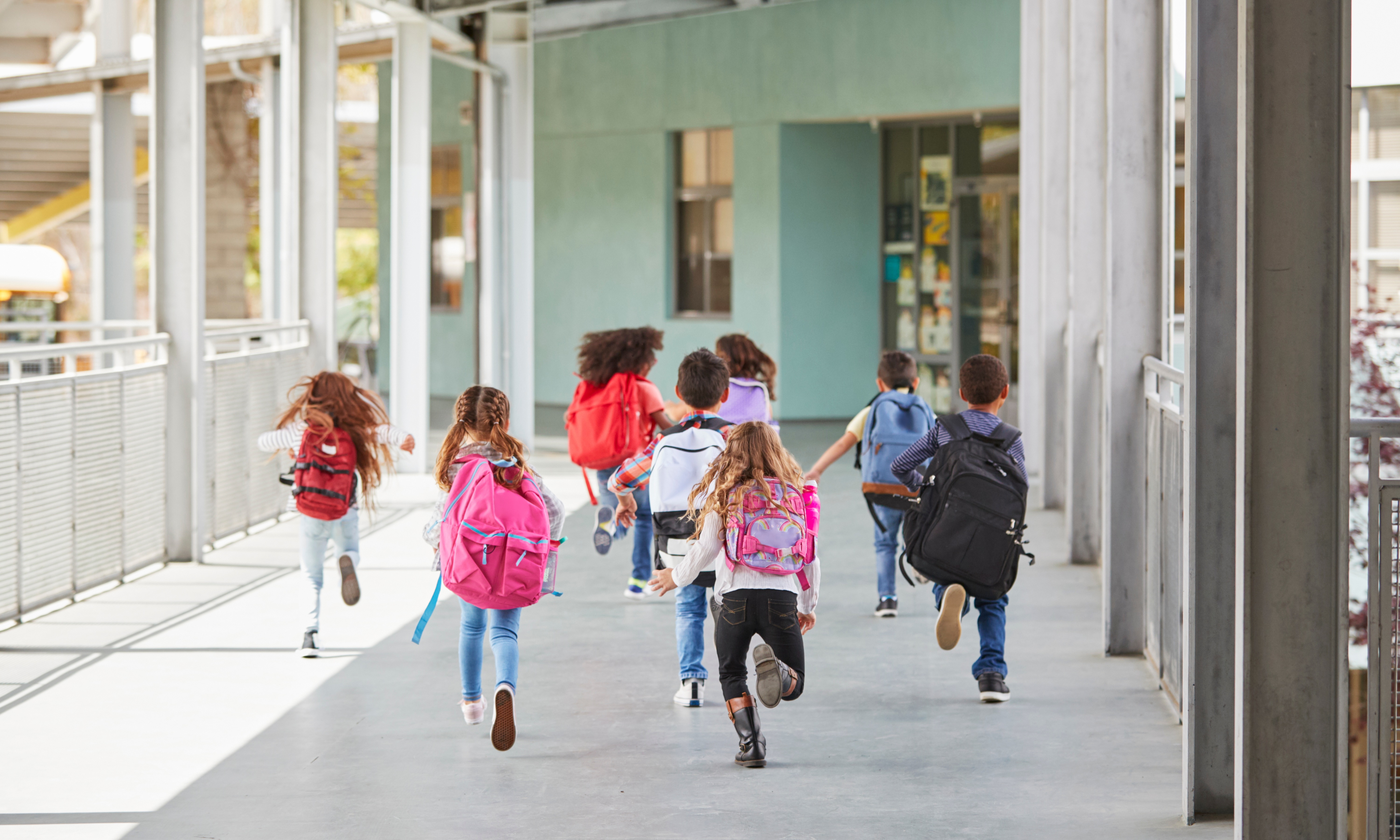 kids running towards the school building with their backpacks