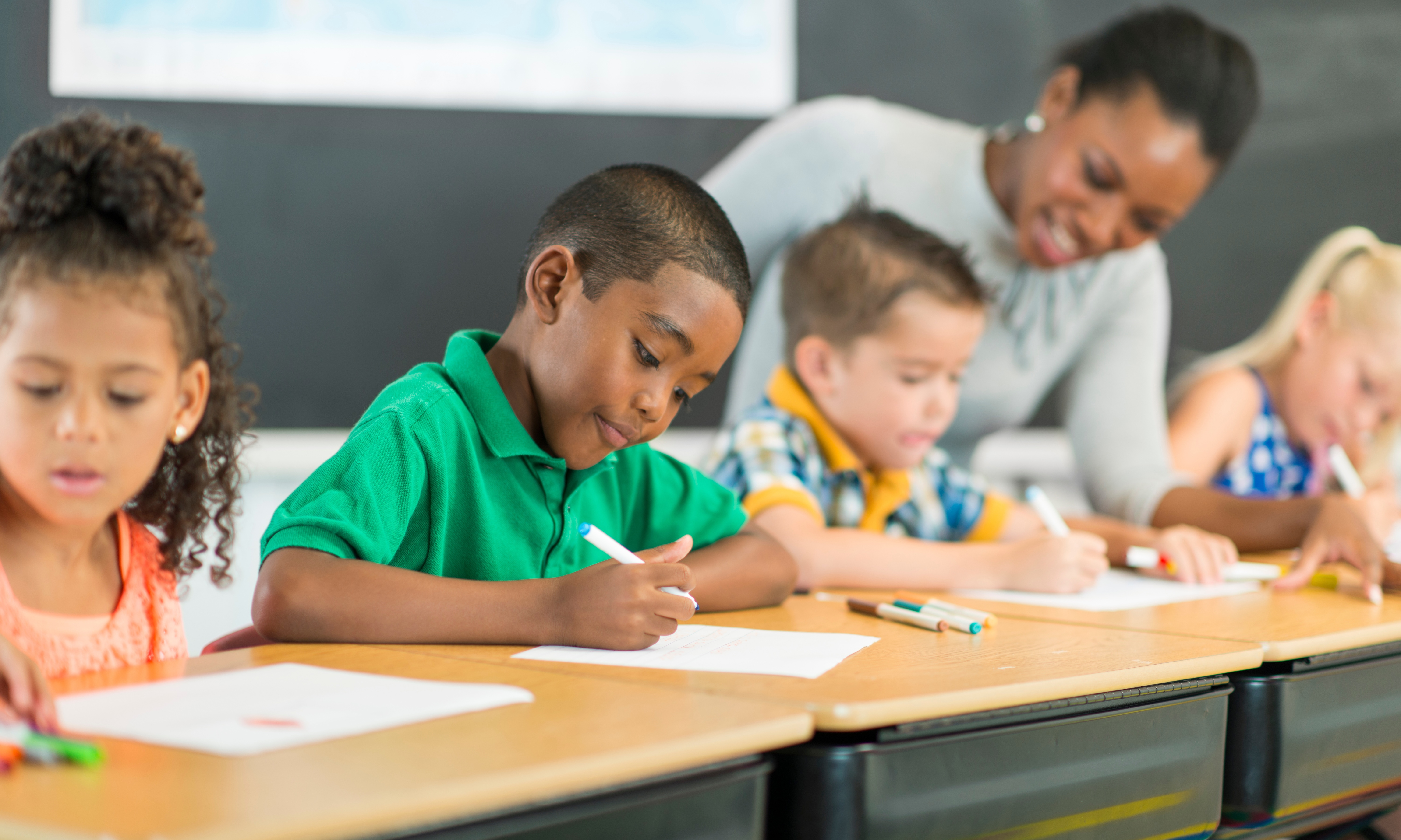 A teacher with students at a desk, focusing on their tasks.