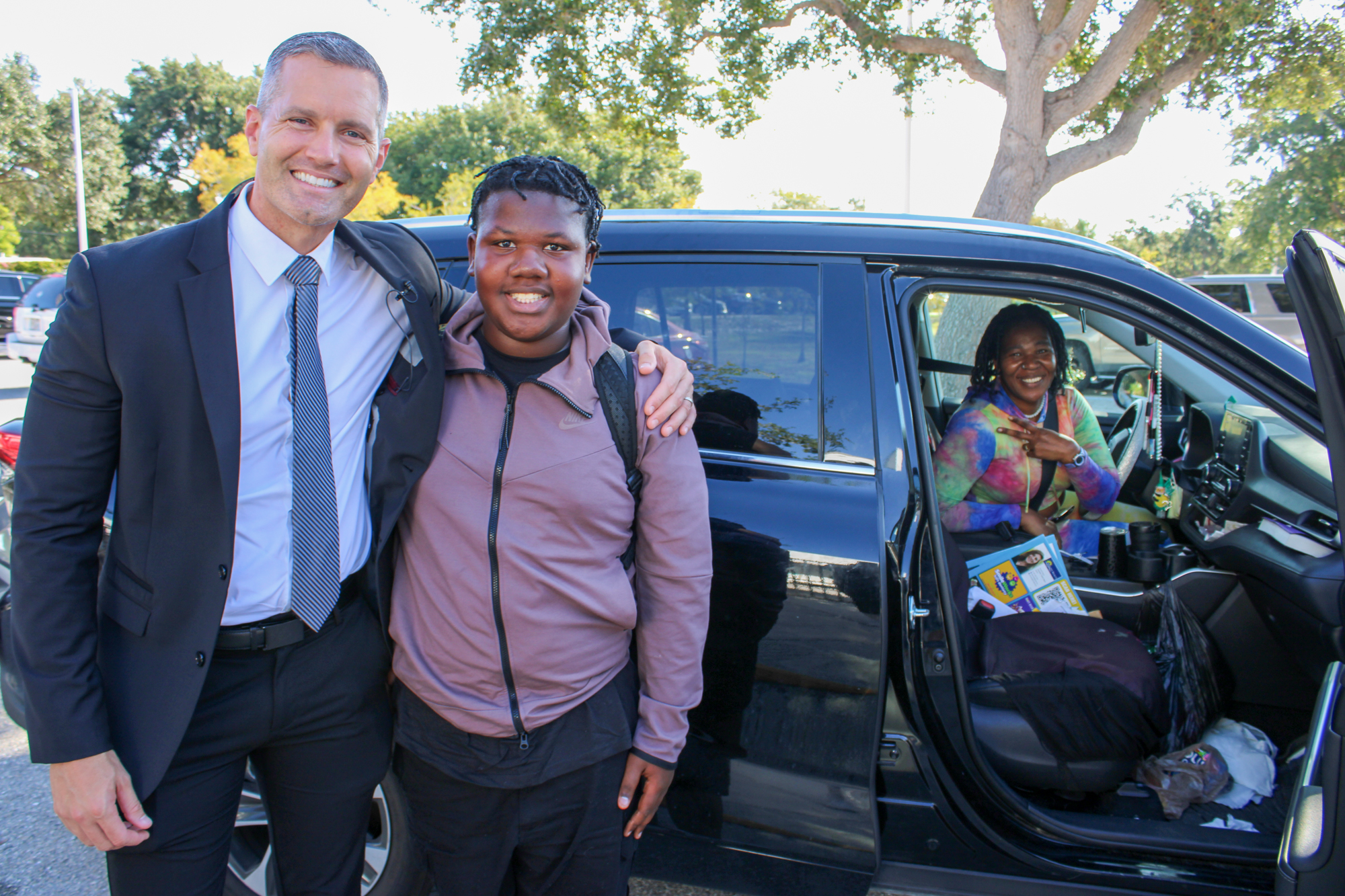 school staff hugging a student in a school parent pick ups zone