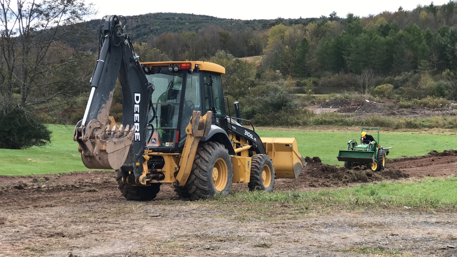 A large yellow and black excavator with a scoop attachment is in the foreground