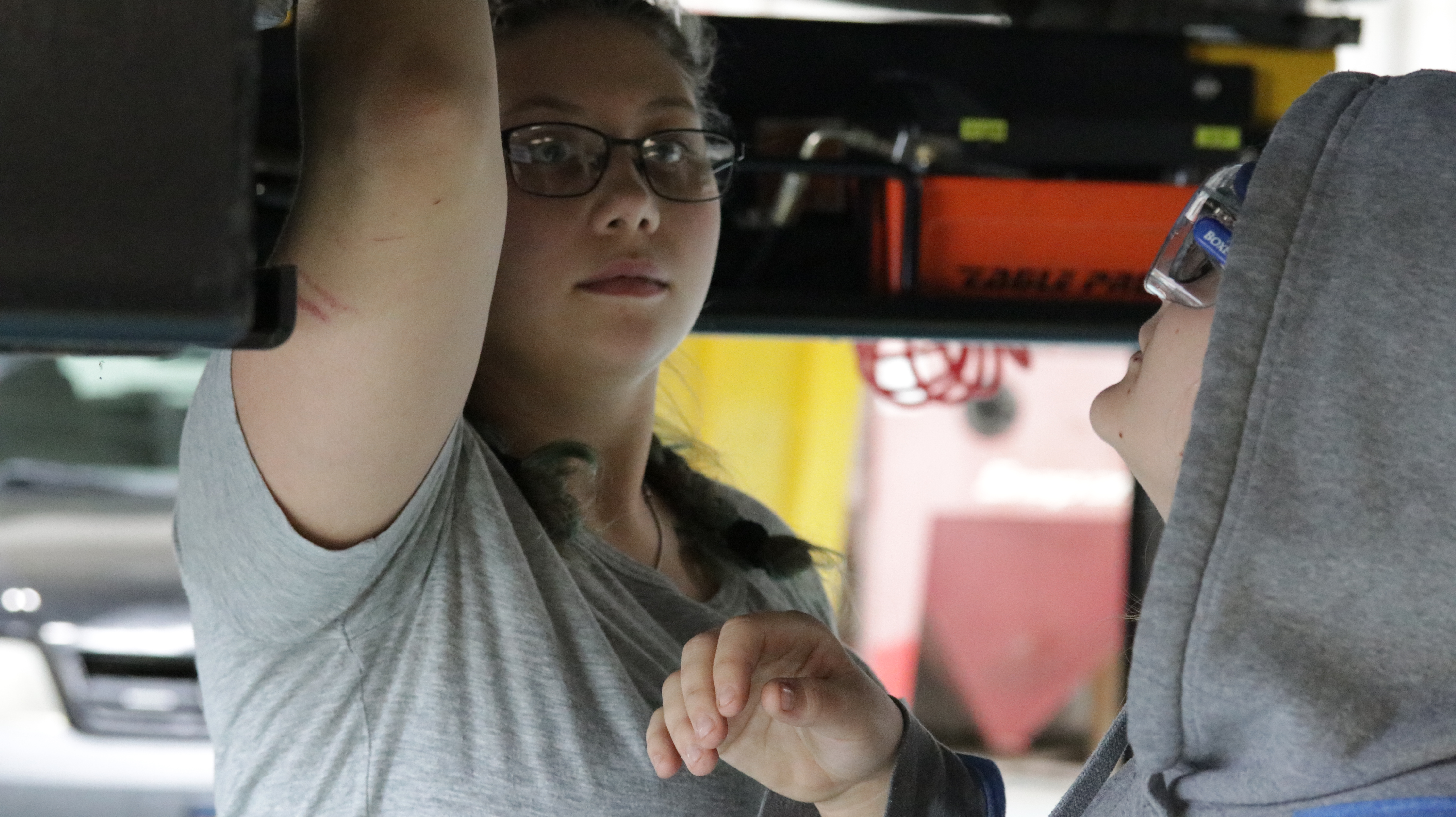 A student working on or inspecting the underside of a vehicle in a garage