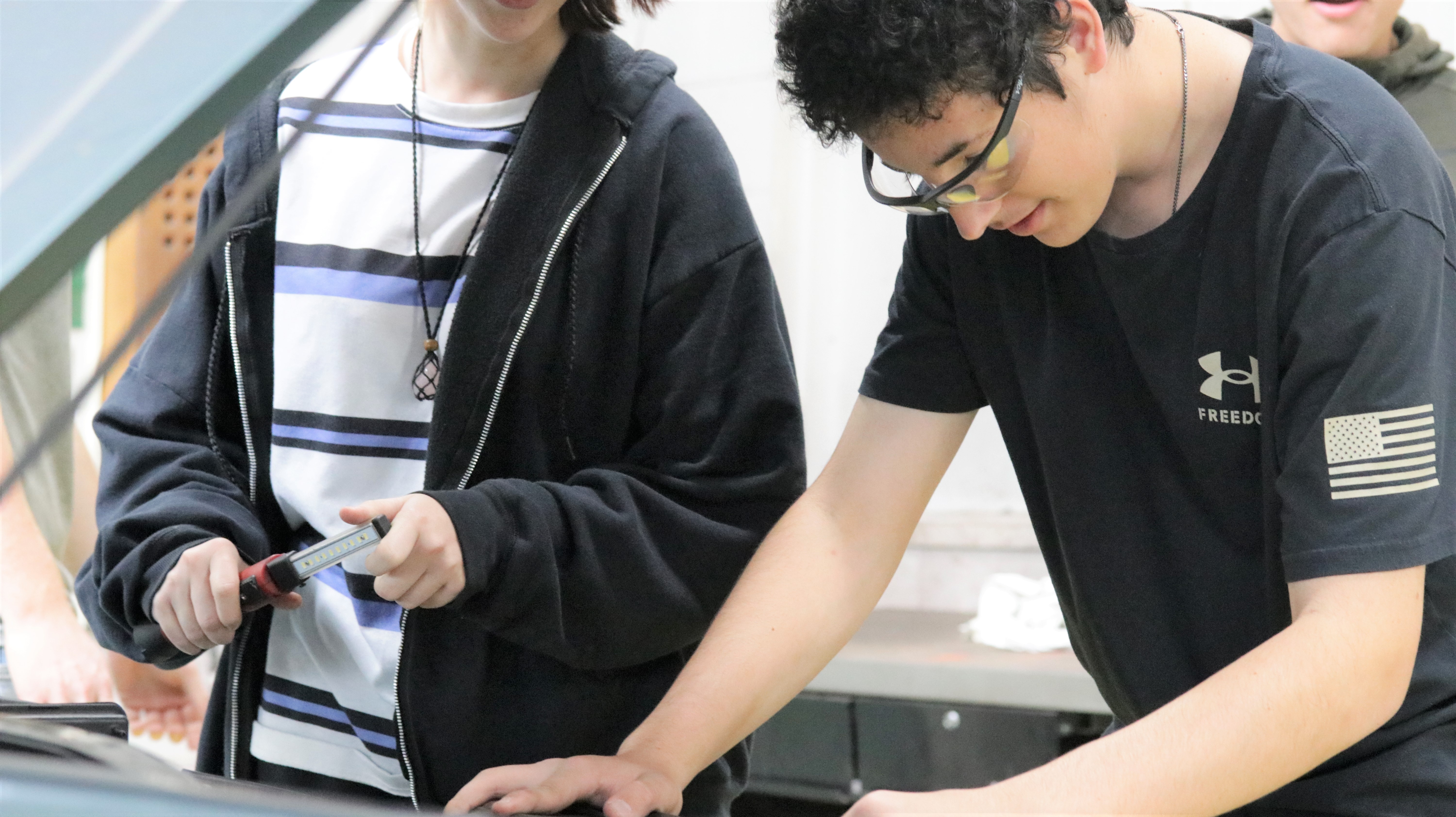 Two individuals fixing an engine of a car