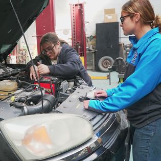 2 girls are fixing a car