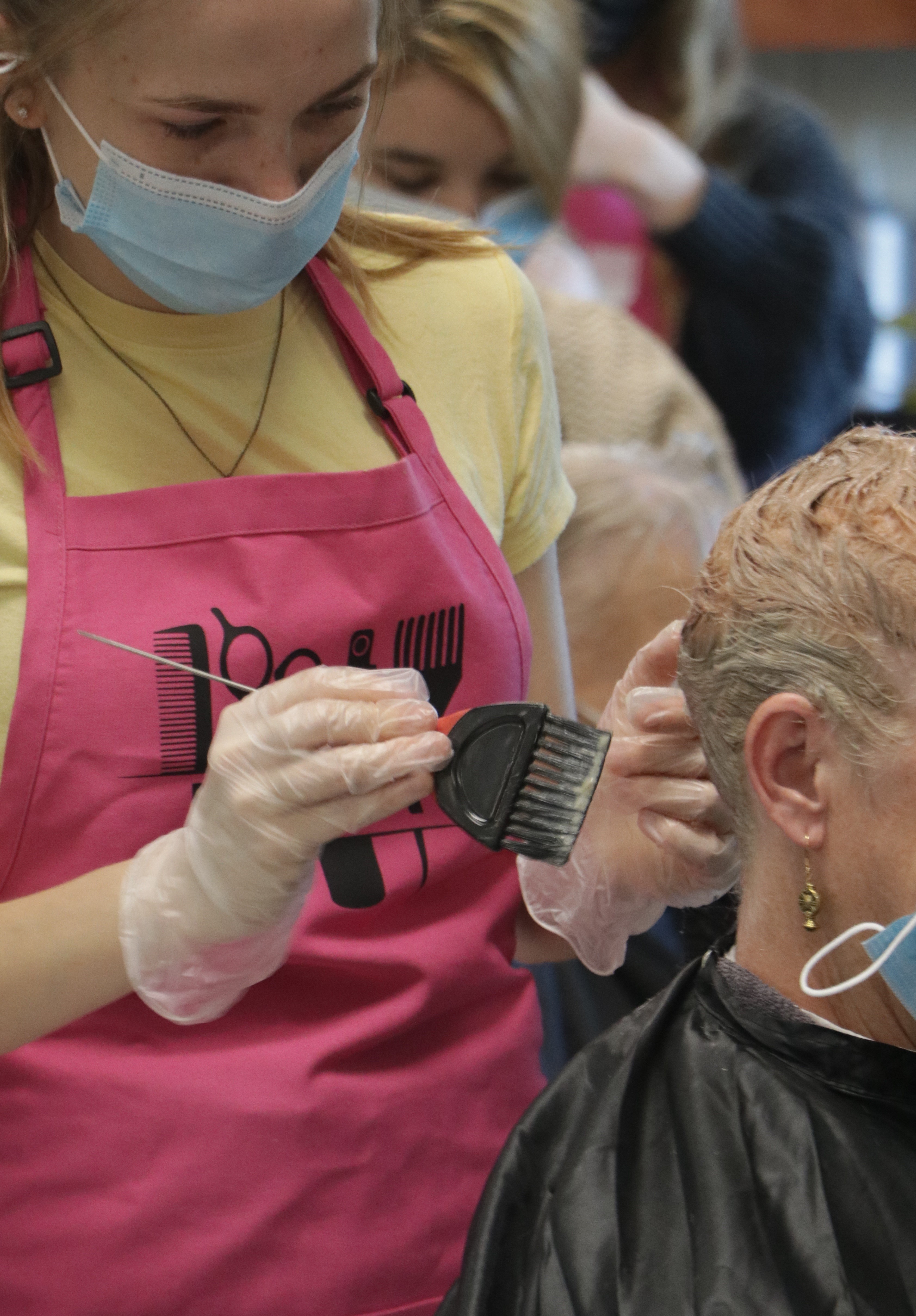 A woman holding a brush and colored the hair of her patron