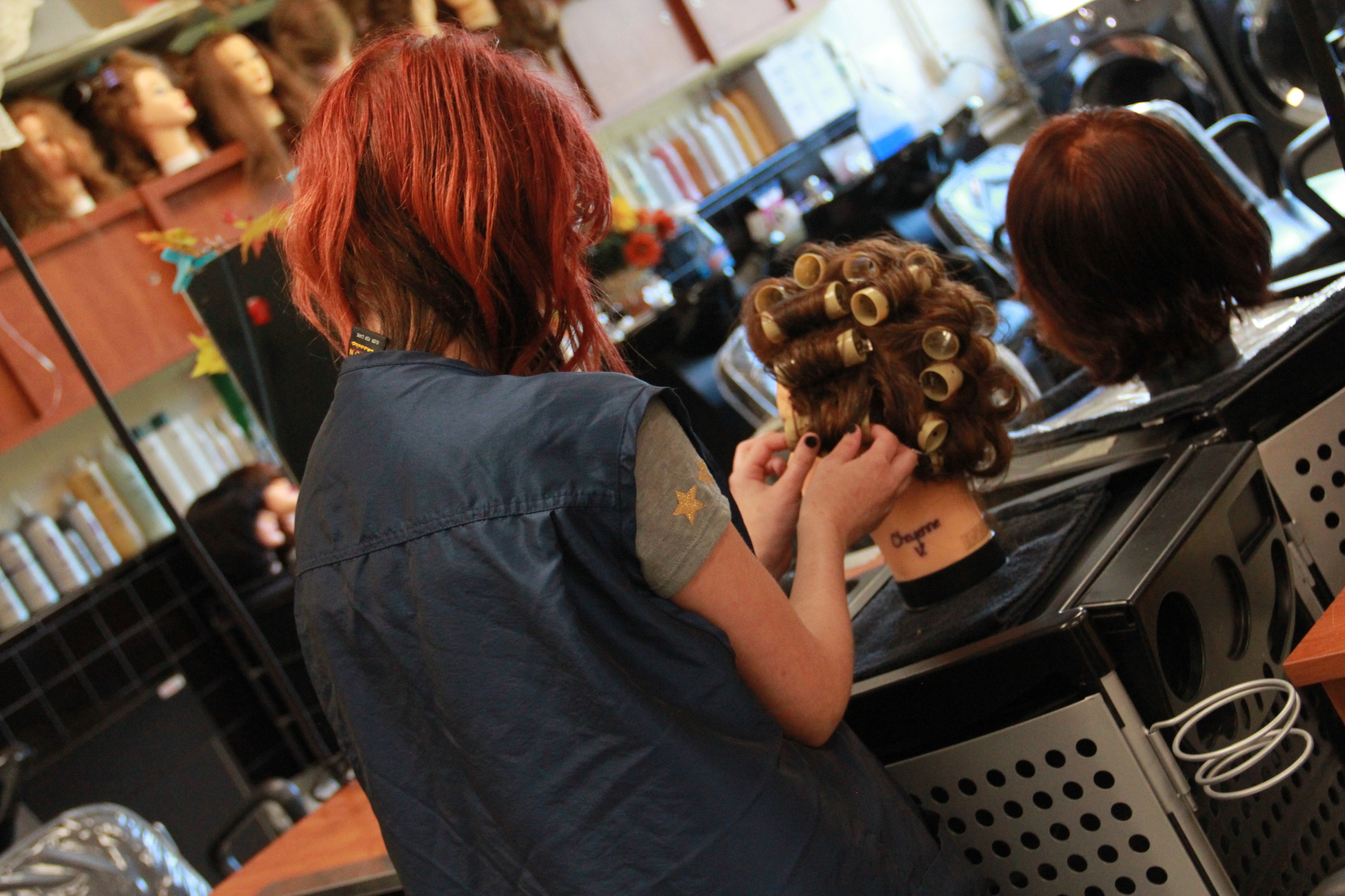 A woman doing curl on a manequine head