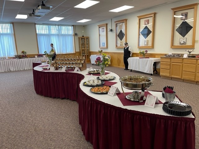 A well-arranged banquet hall with a variety of food displayed on tables covered with burgundy tablecloths