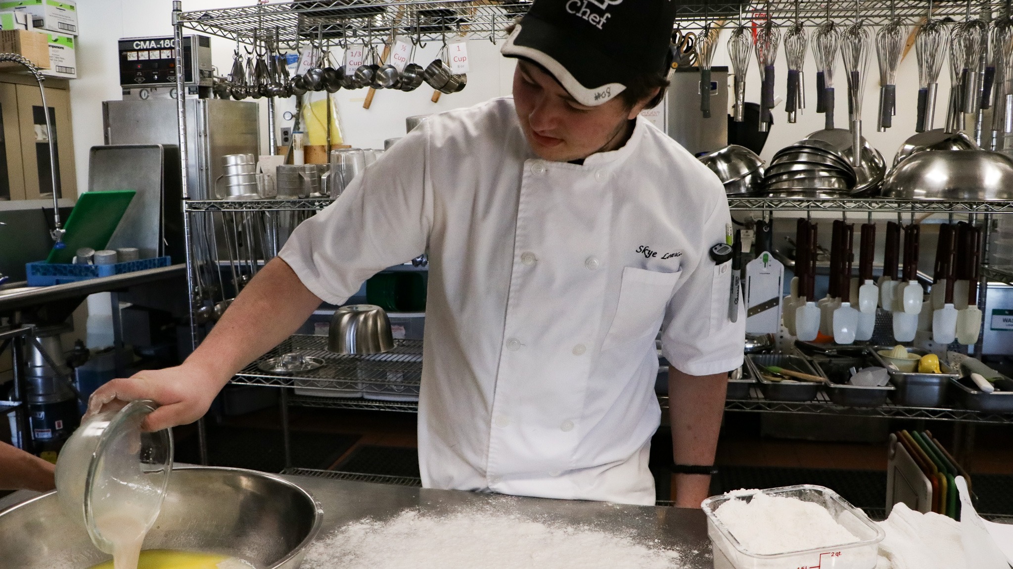 A man holding a bowl of egg white and mixing it to the yolk