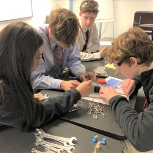 A group of students engaging in a hands-on learning activity, assembling mechanical parts