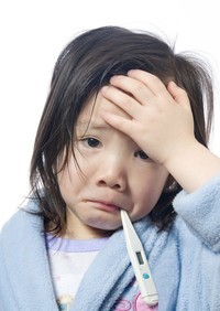 A child wearing a light blue top, holds their head in their hand