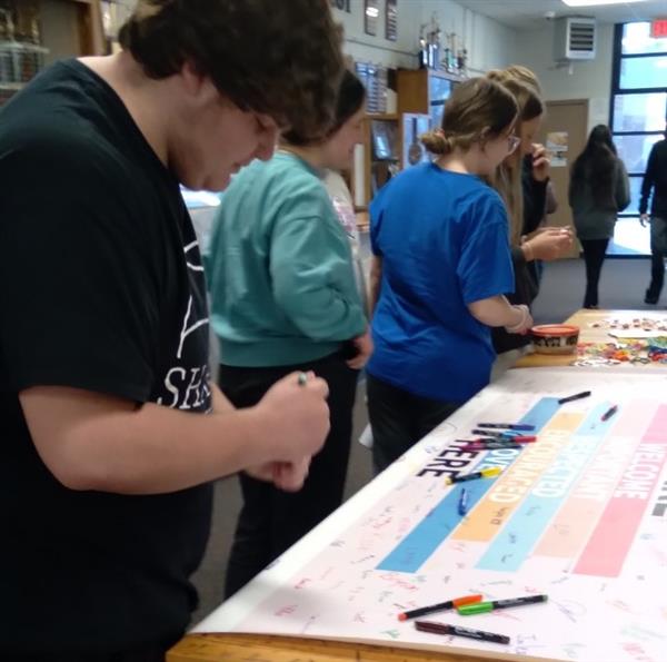 Students creating a poster, using markers and discussing ideas.