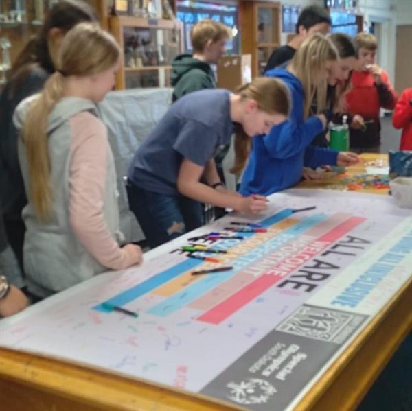 Students creating a poster, using markers and discussing ideas.