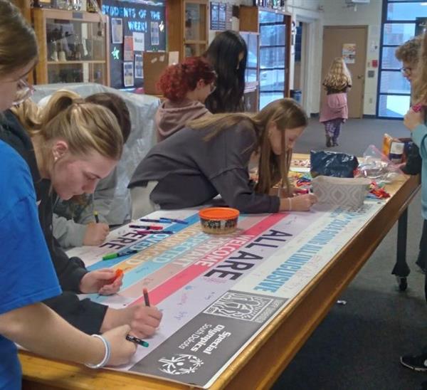 Students creating a poster, using markers and discussing ideas.