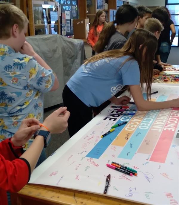 Students creating a poster, using markers and discussing ideas.