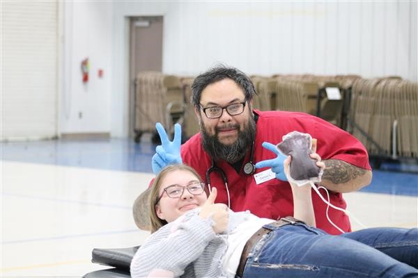 A couple sitting on a bench, with a man holding a heart monitor.
