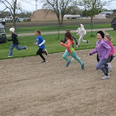 Several children happily running on a dusty path in the countryside.