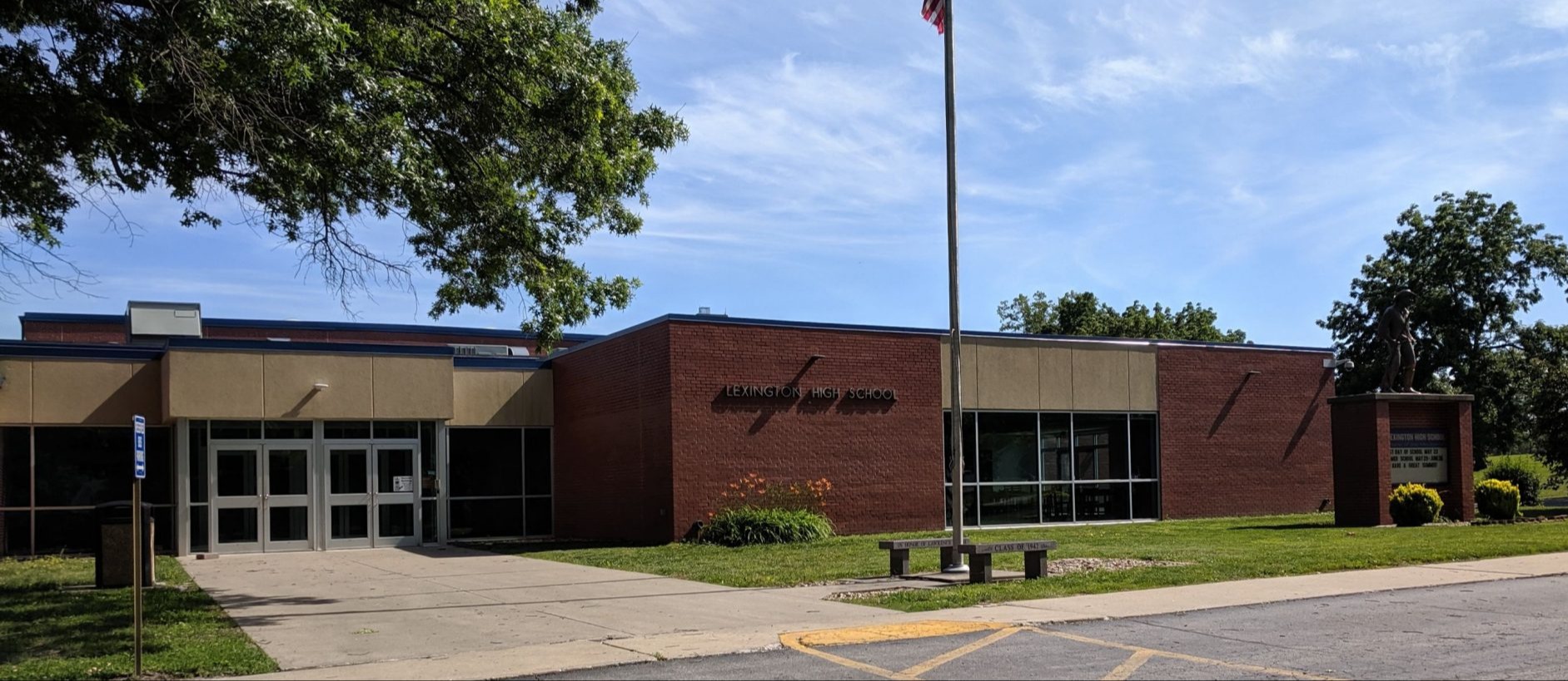 front of high school building with trees and flagpole